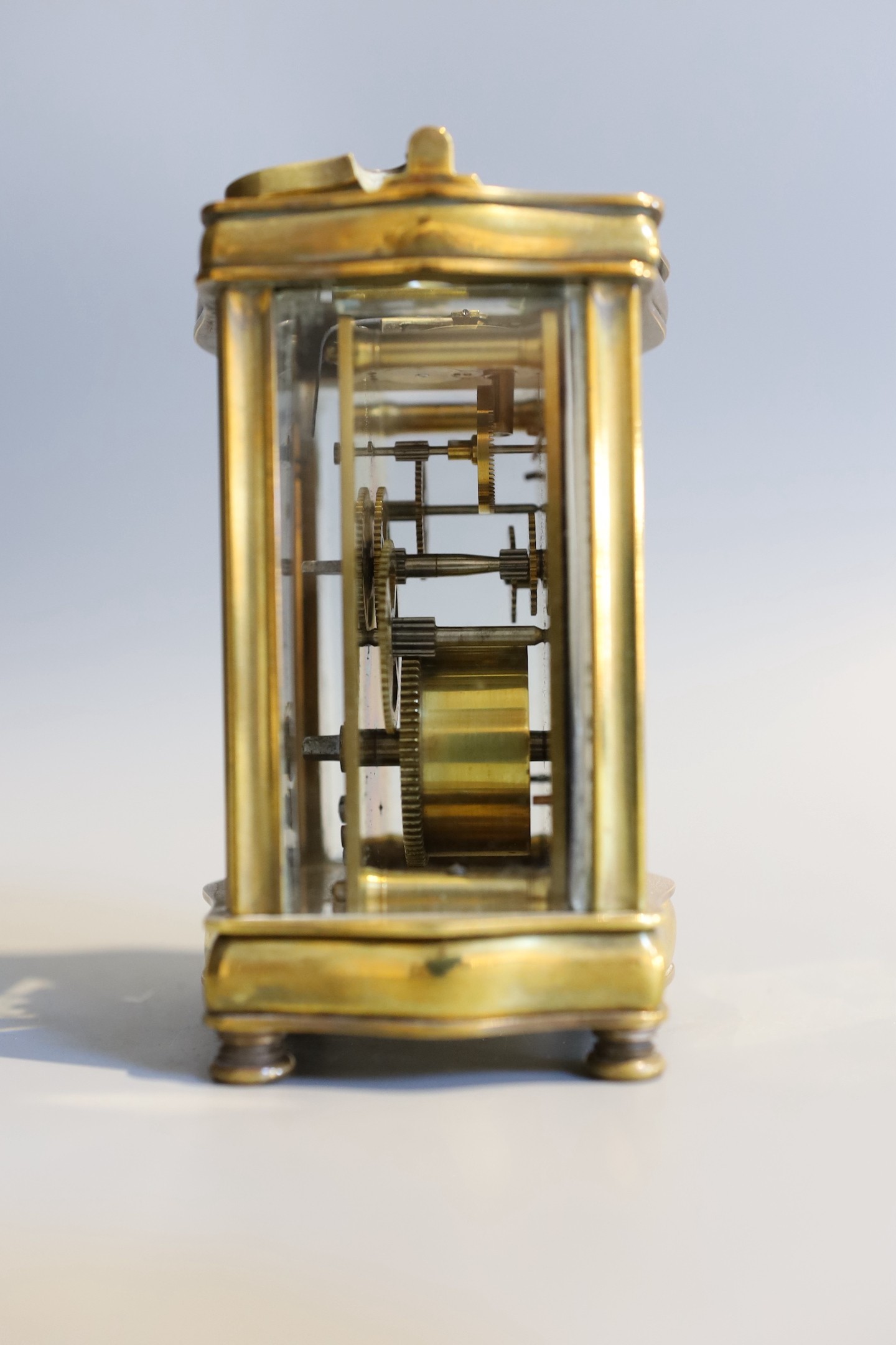 An early 20th century French lacquered brass carriage timepiece, of serpentine form, in red morocco case, height 12cm